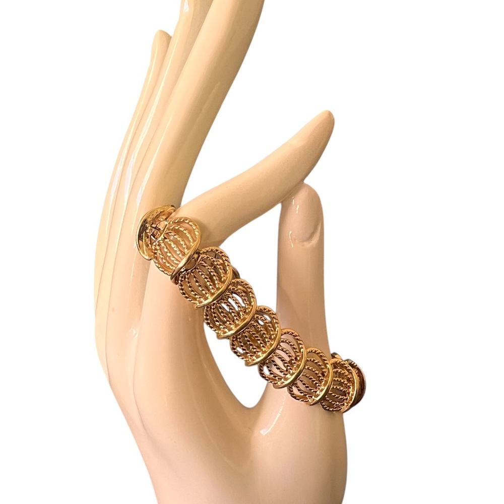 Gold tone Napier Bracelet size 7. Open filigree. Fold over clasp.